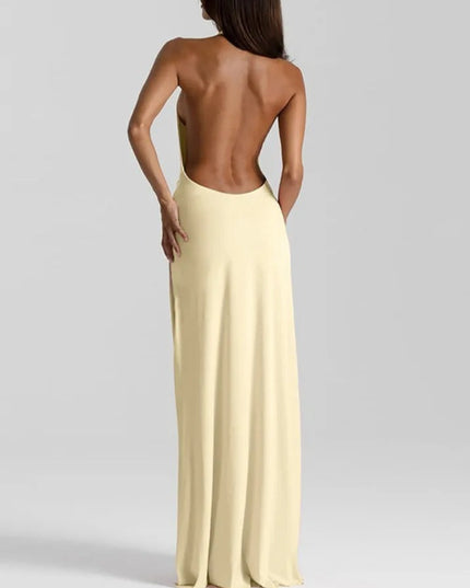 Back view of a pale yellow backless maxi dress with a halter neckline and long flowing skirt.