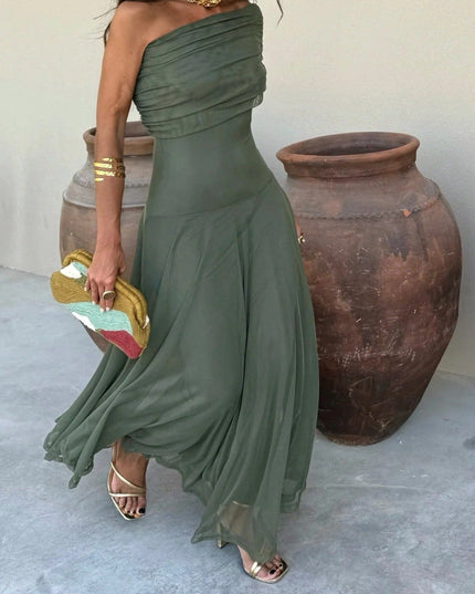 Flowing olive green one-shoulder mesh maxi dress with draped bodice, paired with gold heels and clutch.