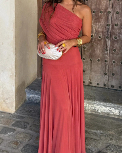 Front view of a women's coral red one shoulder drape mesh maxi dress, paired with a white pearl clutch.