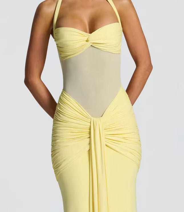 Close-up of a women's light yellow halter neck maxi dress with ruched details and sheer mesh midriff.