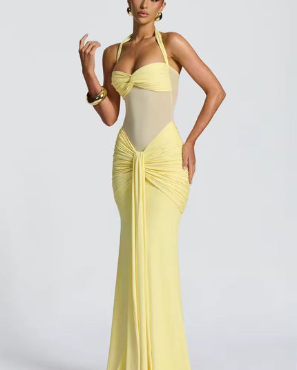 Side view of a women's light yellow prom dress, showcasing the halter neck, ruched mesh details, and the elegant drape of the maxi skirt.
