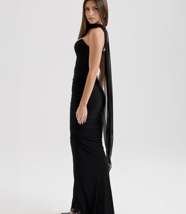 Side profile of a black strapless mesh ruched maxi dress, showcasing the floor-length skirt and sheer fabric.