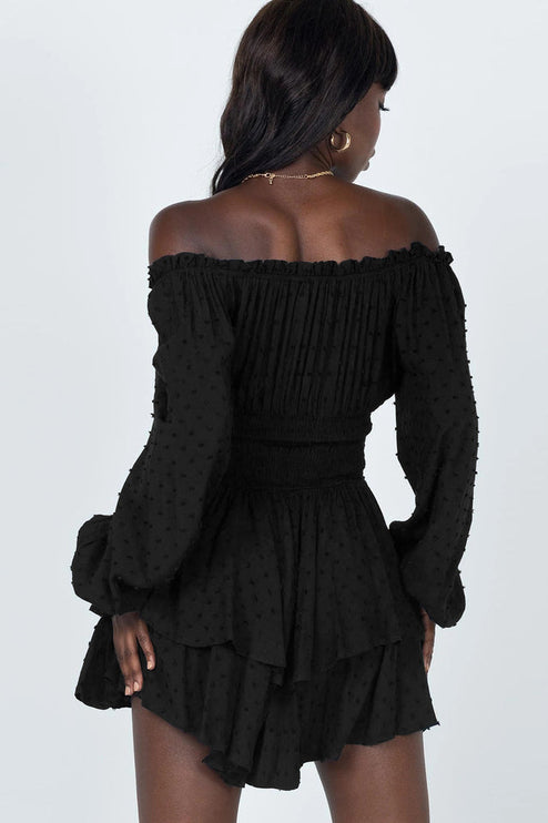 Back view of black off-shoulder mini dress, showing shirred waist and tiered skirt
