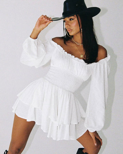 White off-shoulder long sleeve mini dress with smocked waist and tiered skirt, styled with a black cowboy hat and black boots.