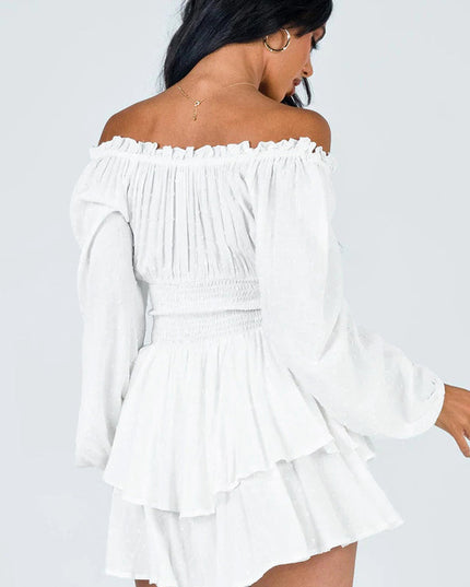 Back view of a white off-shoulder long sleeve mini dress, highlighting the smocked back and tiered ruffled skirt design.