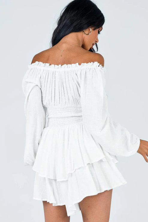 Back view of a white off-shoulder long sleeve mini dress, highlighting the smocked back and tiered ruffled skirt design.