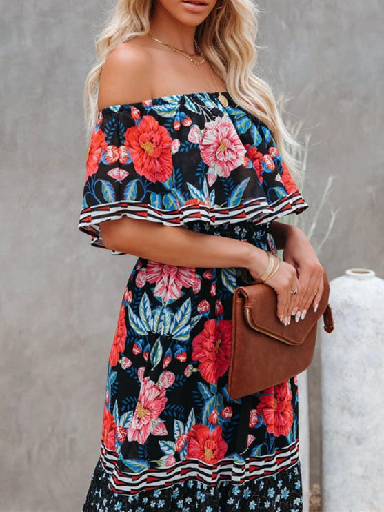 Close-up of the bodice of a women's black floral off-shoulder ruffled maxi dress, with vibrant red and pink blooms.