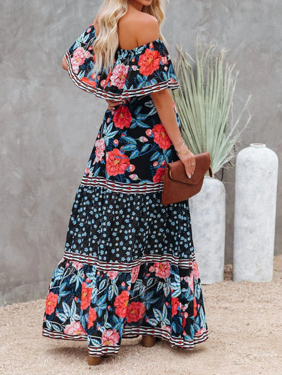 Back view of a women's black floral off-shoulder maxi dress, showing the ruffled neckline and tiered skirt design.