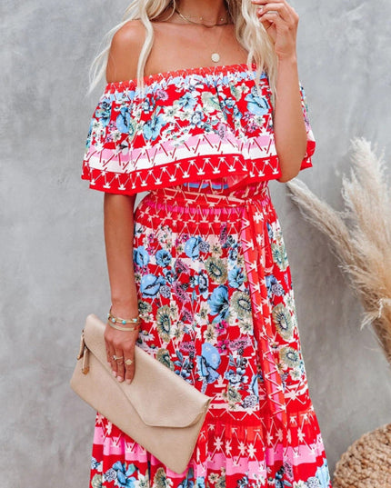 Close-up of red floral off-shoulder ruffled maxi dress with blue and white patterns, holding a beige clutch.