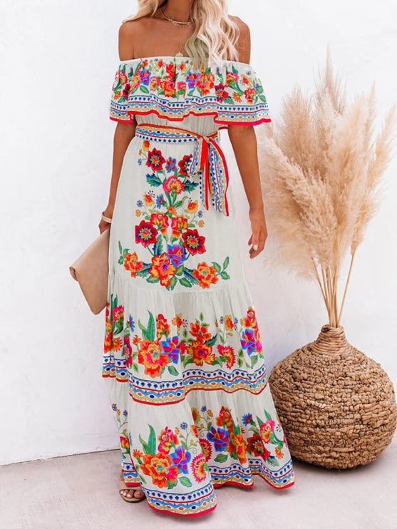 Full-length view of a women's off-shoulder floral maxi dress in white with colorful embroidery and a red waist tie.