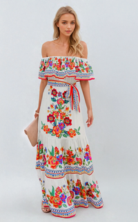 Women's off-shoulder ruffled maxi dress in white with vibrant red, orange, and blue floral print, tied at the waist.