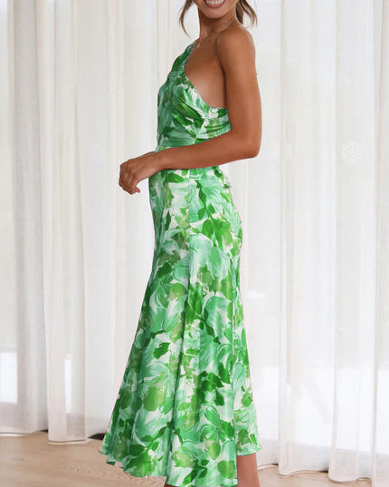 Side profile of a woman in a green and white floral one-shoulder midi dress, highlighting the elegant silhouette.