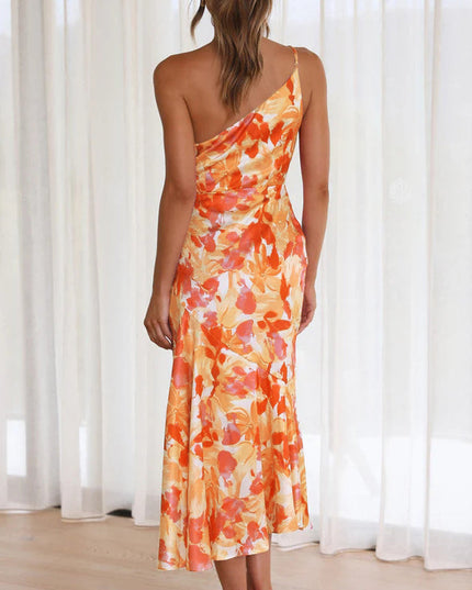 Back view of a woman in an orange and white floral one-shoulder ruched bust midi dress, with a graceful drape.
