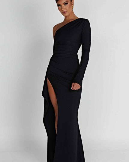 Angled view of a black one-shoulder long sleeve maxi dress with a side slit and subtle draping.