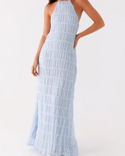 Side view of the light blue open back halter neck maxi dress, showing the flow of the skirt.