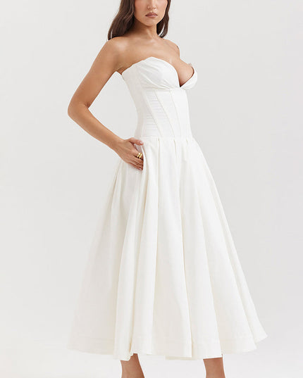 Profile view of a white strapless midi dress, highlighting the structured boned bodice and flowing pleated skirt.