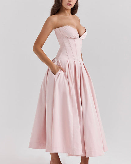 Profile view of a pink strapless midi dress, highlighting the boned bodice, pleated skirt, and functional pockets.
