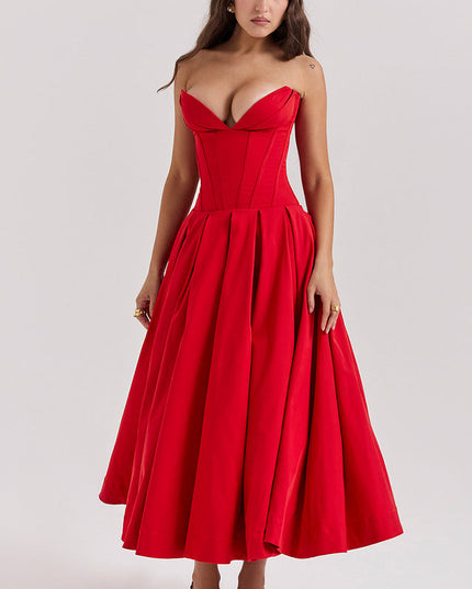 Front view of a woman in a vibrant red strapless boned bodice pleated midi dress and black slingback heels.