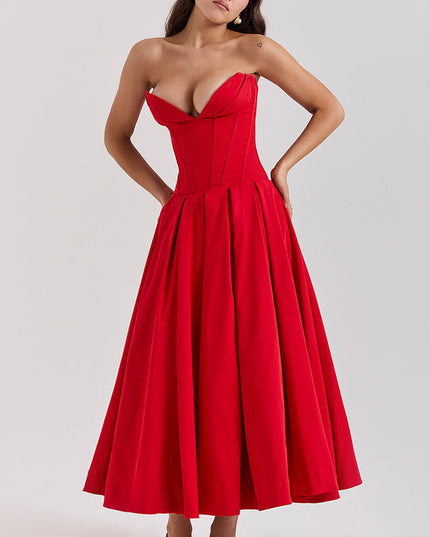 Woman posing with hands on hips in a red strapless boned bodice pleated midi dress, showcasing the full skirt.