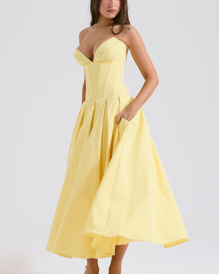 Side view of a women's light yellow strapless boned bodice pleated midi dress, showing pockets