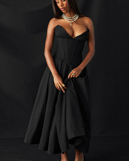 Black strapless boned bodice midi dress with pleated skirt, worn with pearl necklace on dark background.