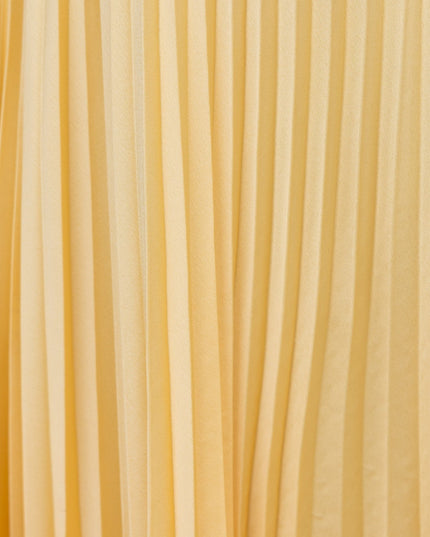 Close-up texture of the yellow pleated fabric on the maxi dress, showing vertical folds.