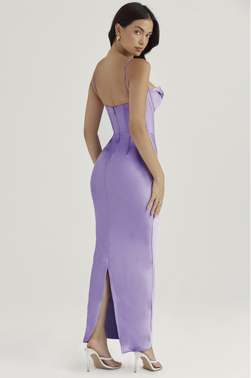 Back view of a lavender satin maxi dress with a corset bodice and delicate spaghetti straps, featuring a subtle back slit and worn with white heels.