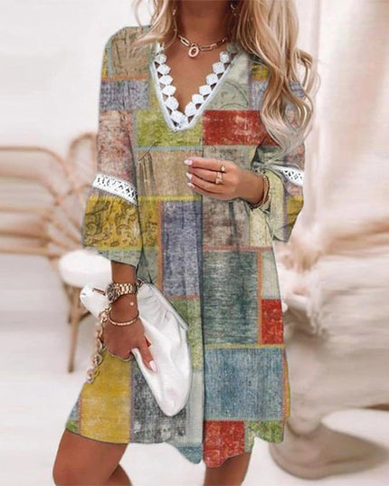 Women's summer mini dress with a colorful patchwork design in muted tones, V-neck, and white lace detail.
