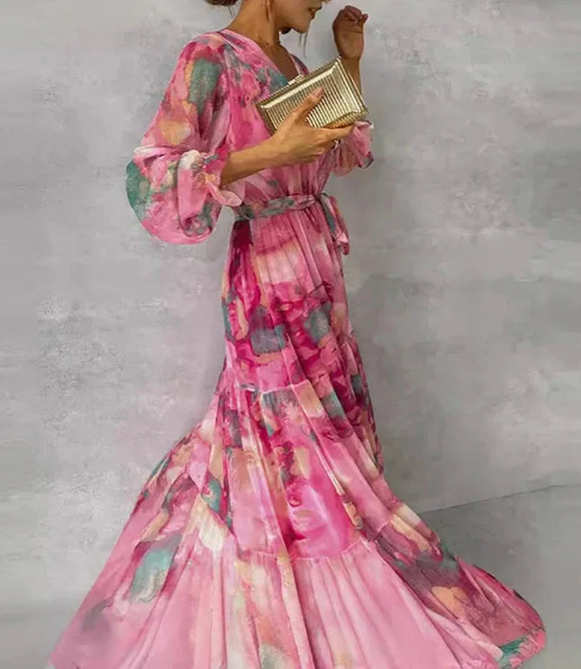 Side profile of a women's flowing pink floral V-neck maxi dress with long bishop sleeves and a cinched waist.