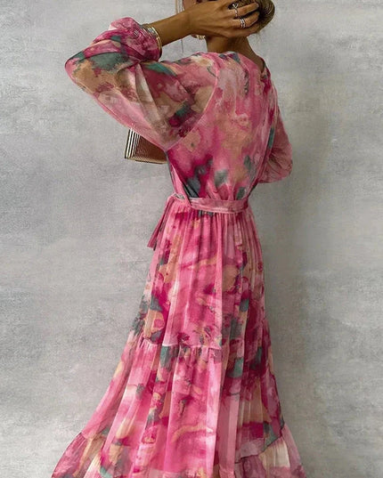 Back view of a women's pink floral printed V-neck long sleeve maxi dress, showing the flowy tiered skirt.