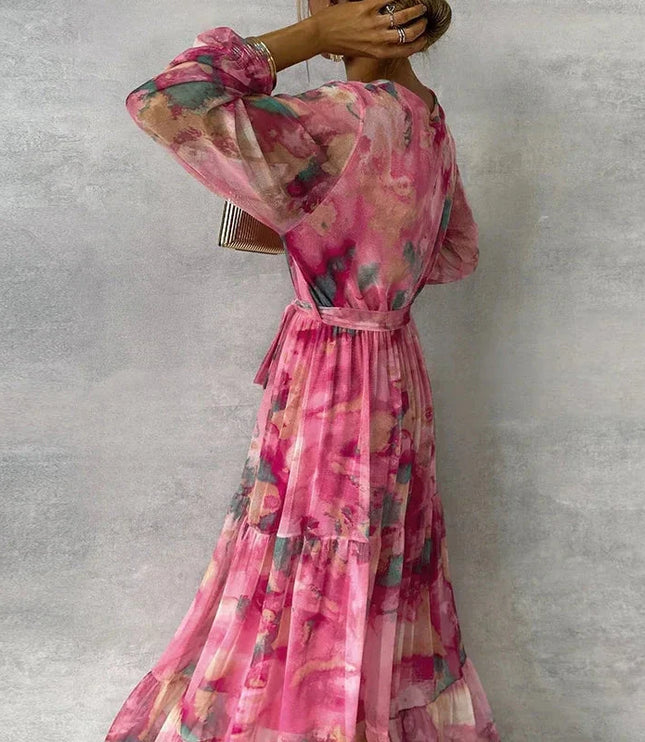 Back view of a women's pink floral printed V-neck long sleeve maxi dress, showing the flowy tiered skirt.