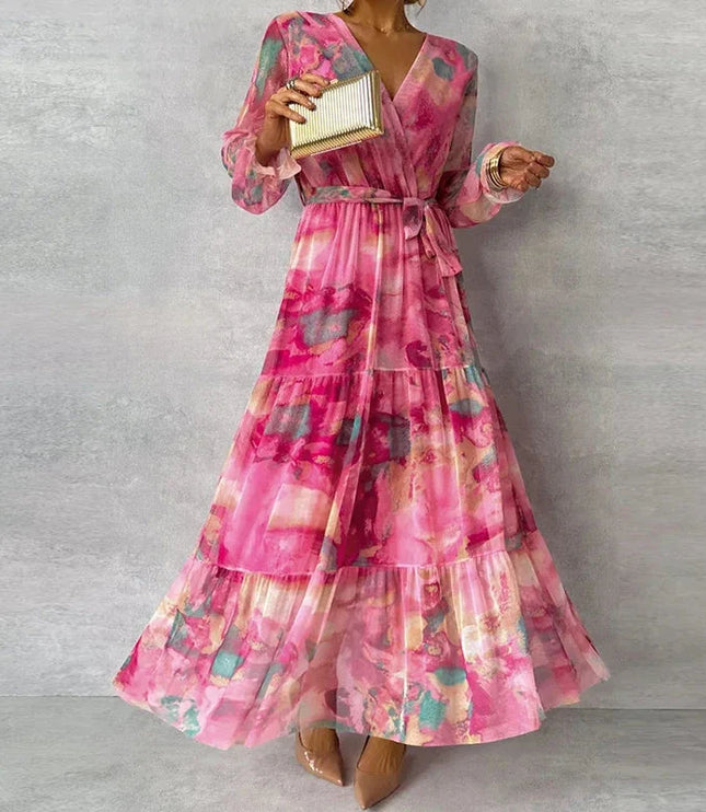 Front view of a women's elegant pink floral V-neck long sleeve maxi dress with a full, tiered skirt and tie waist.