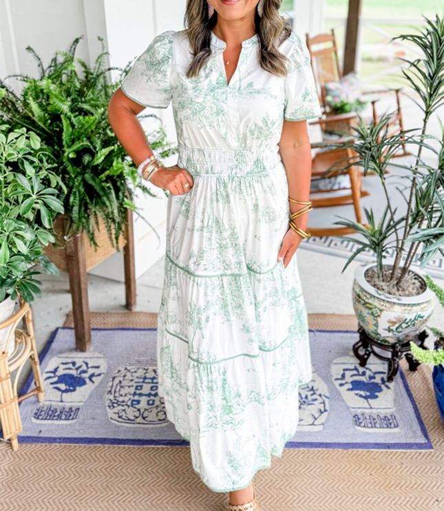 Women's white summer maxi dress with light green scenic print, v-neck, short sleeves, and smocked waist, with woven slides.