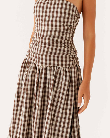 Close-up of the ruched bodice and flowing skirt on a brown and white gingham strapless maxi dress