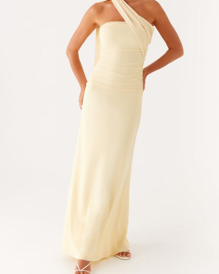 Full-length view of a women's strapless ruched neck scarf maxi dress in pale yellow, with hands on hips.