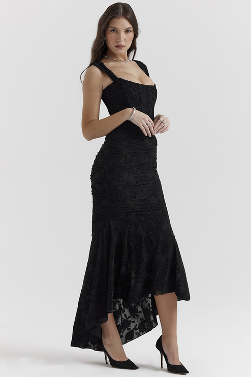 Side view of a women's black floral ruched maxi dress, highlighting the elegant silhouette and high-low hem.