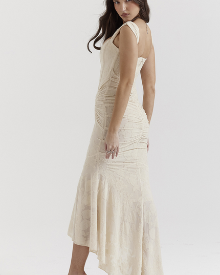 Side profile of a women's cream floral ruched maxi dress, featuring a high-low hem and subtle train.