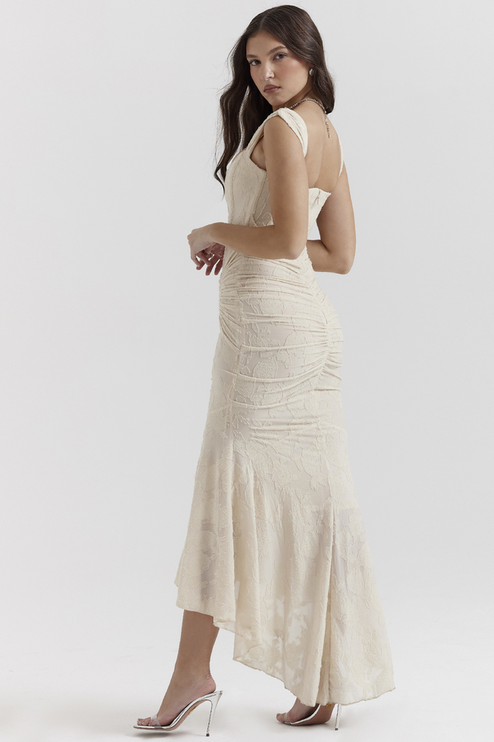 Three-quarter view of a cream floral ruched maxi dress, highlighting the fitted bodice and flowing skirt.