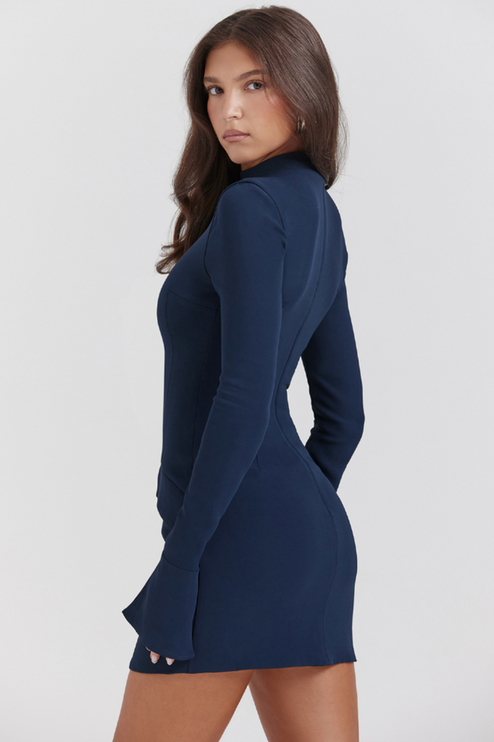 Side profile of a navy blue mock neck mini dress, showcasing the fitted silhouette and long sleeves with ruffle cuffs.