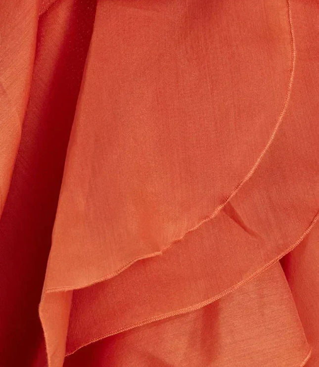 Close-up detail of the coral fabric and layered ruffles of the strapless maxi dress, showing the texture and construction of the flowing tiers.