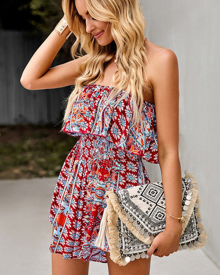 Women's red floral strapless ruffle mini romper with a smocked waist, holding a decorative clutch with tassels.