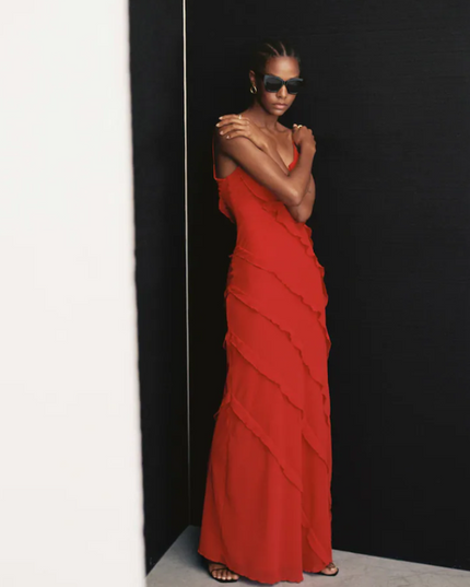 Front view of a red V-neck ruffle side slit maxi dress with layered ruffles and thin straps, worn with sunglasses