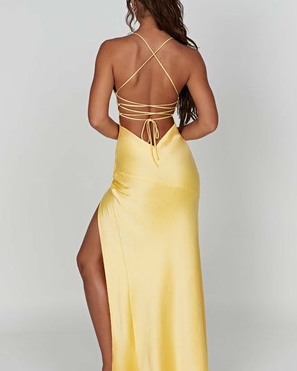Angled back view of the yellow satin maxi dress, showing the tie-back and the subtle high slit from behind.