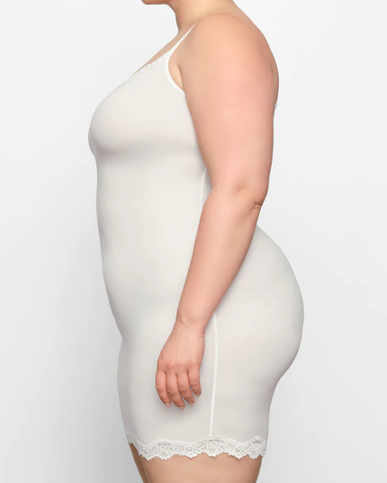 Side profile of a plus-size woman in the ivory lace trim scoop neck mini slip dress, showcasing the garment's drape.