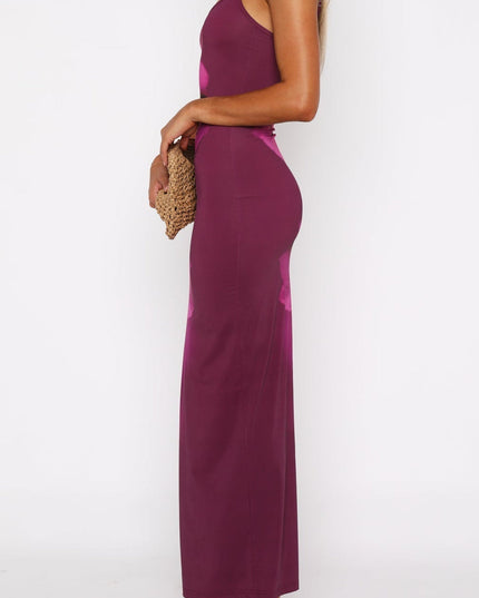 Side profile of a women's magenta floral maxi dress with spaghetti straps and a scoop neckline, holding a woven clutch.