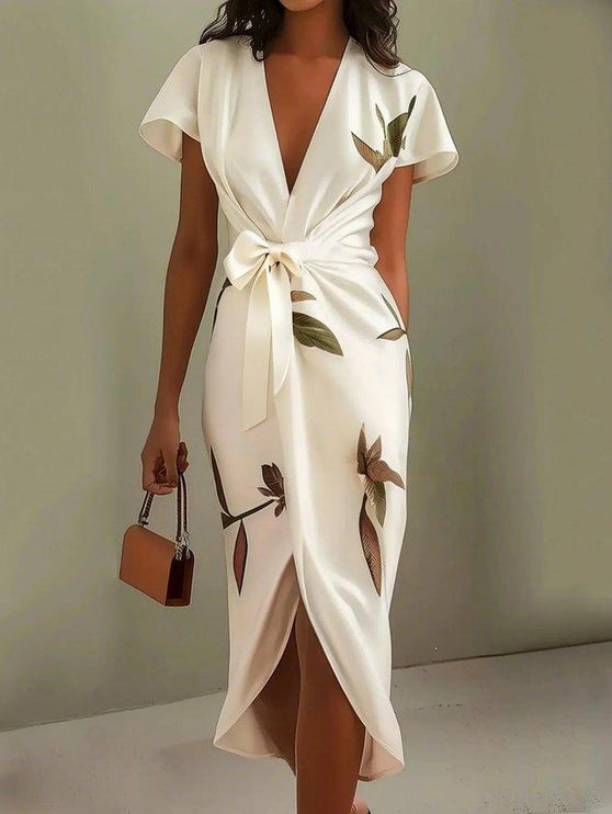 Full-length view of a women's white leaf print v-neck short sleeve midi wrap dress, featuring a front tie.