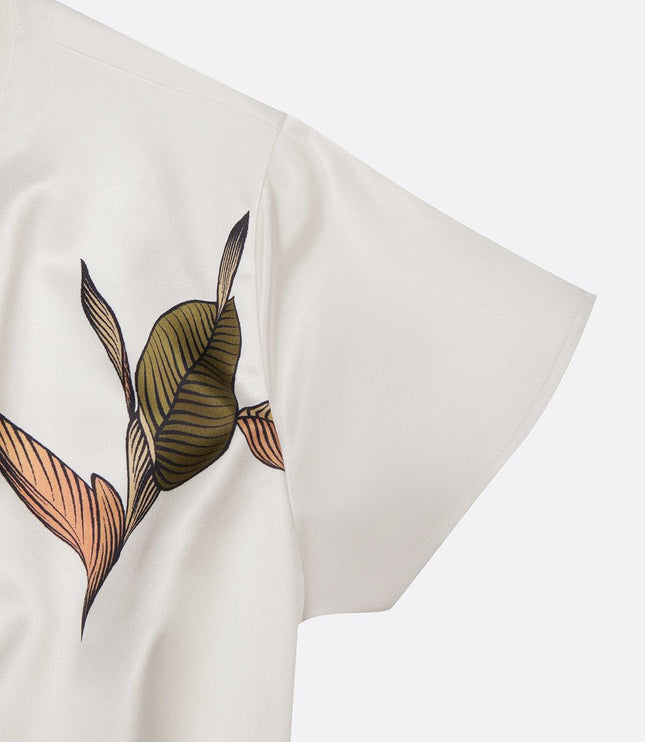 Close-up detail of the short sleeve and leaf print on the white midi wrap dress fabric.