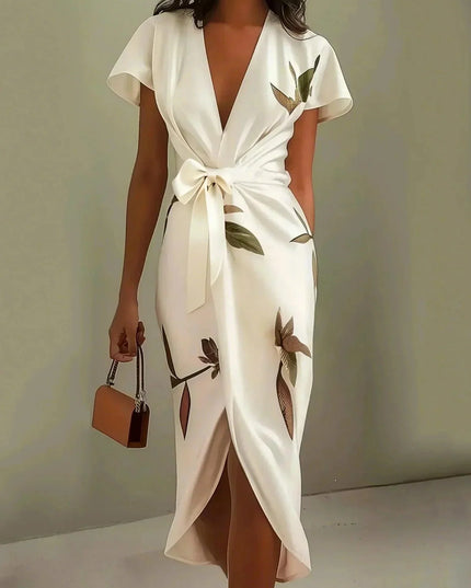 Women's white leaf print v-neck short sleeve midi wrap dress with a tied waist, holding a brown purse.