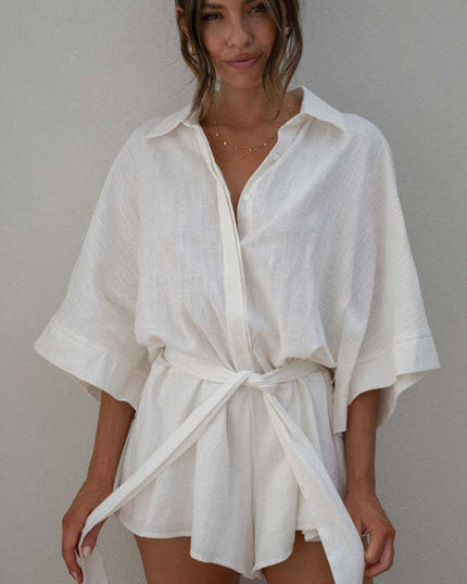 Front view of a white summer collared button-front short romper with a self-tie belt, showcasing the light fabric.