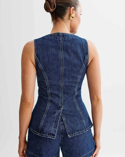 Back view of a sleeveless dark wash denim top with a peplum hem, showing seam details and matching denim shorts.